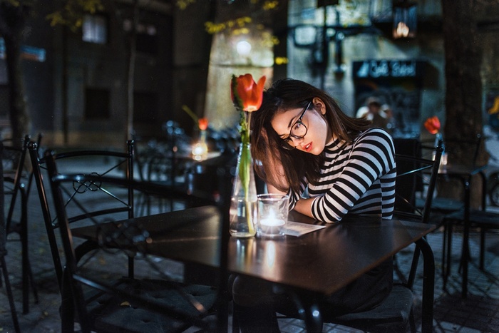 Woman with glasses at a table with a flower