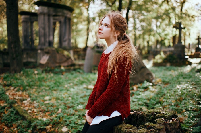 Woman with long blonde hair in a red sweater in a cemetery