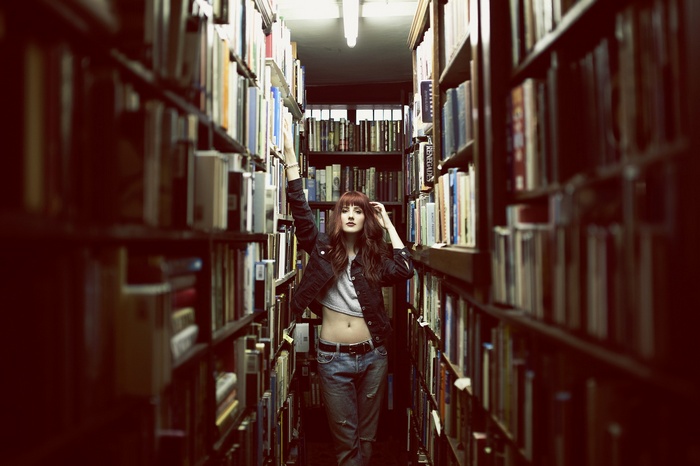 Redhead woman in denim jacket and jeans in library aisle