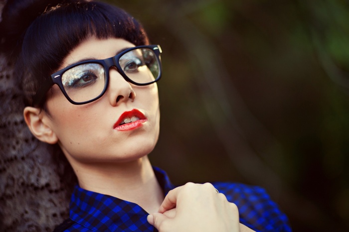 Woman with glasses and red lipstick outdoors