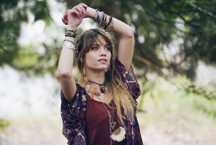 Woman with arms up wearing jewelry outdoors