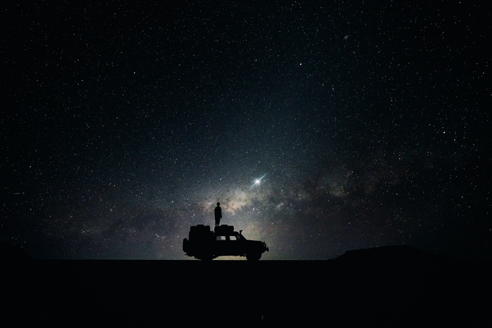Person standing on a car under the starry night sky