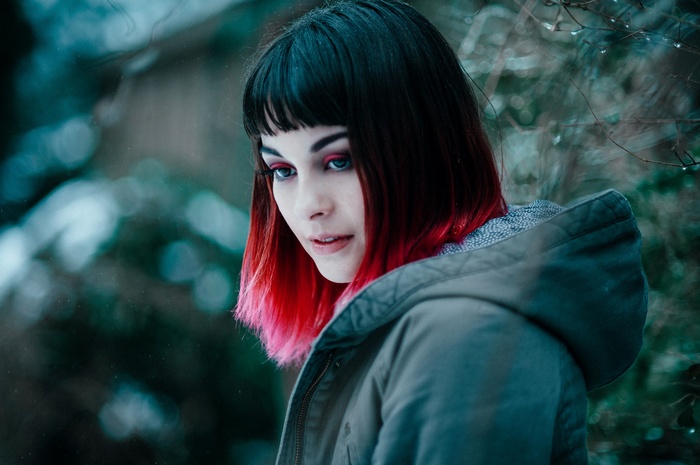 Woman with black and red dyed hair wearing a jacket outdoors