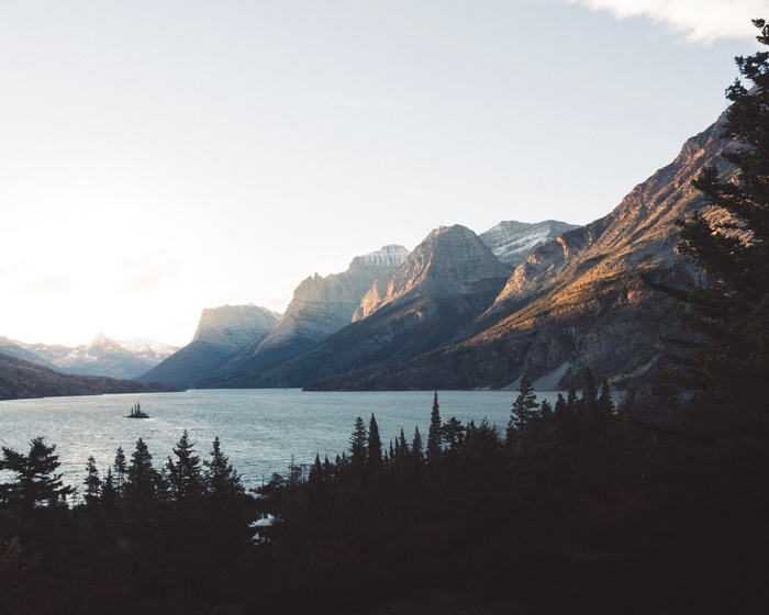 Lake and mountains at sunset with trees in foreground