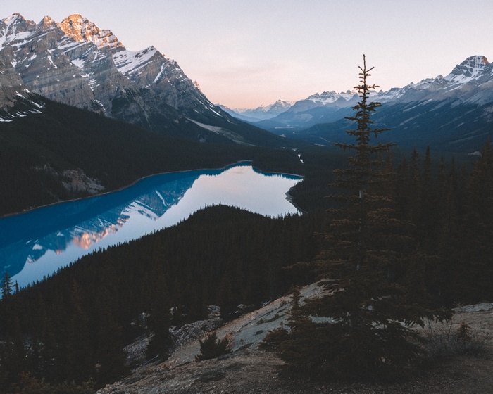 Snow-capped mountains reflecting in a blue lake surrounded by trees
