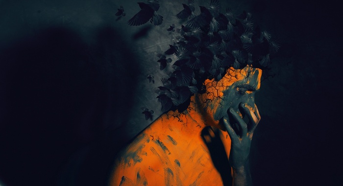 Man with crows flying from head, orange and dark body paint