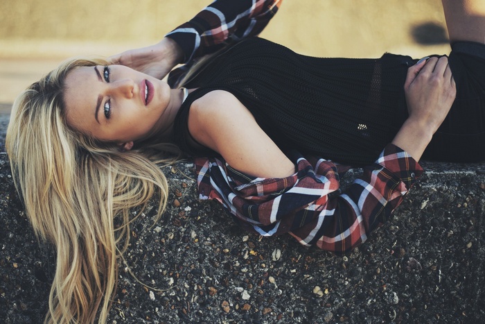 Woman with blonde hair wearing a plaid shirt lying down