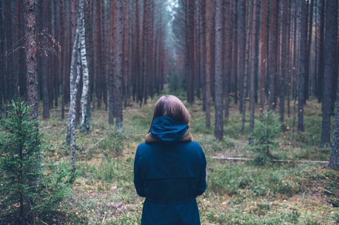 Woman in blue coat in a pine forest