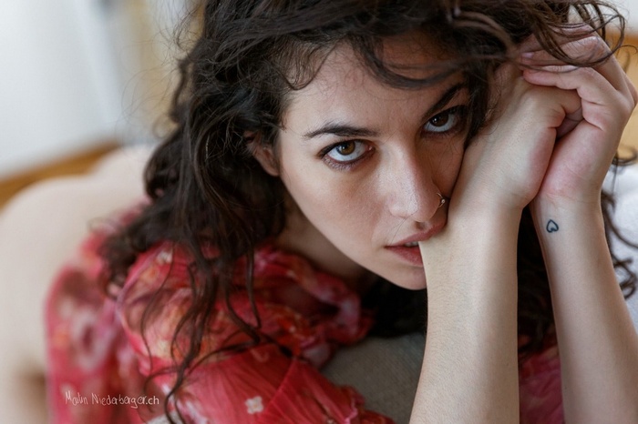 Woman with dark curly hair and a heart tattoo