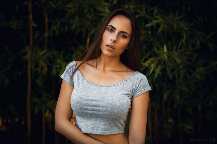 Woman with long brown hair wearing a grey crop top