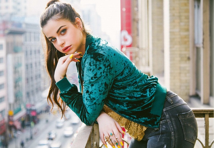 Young woman with dark hair and blue eyes on a balcony