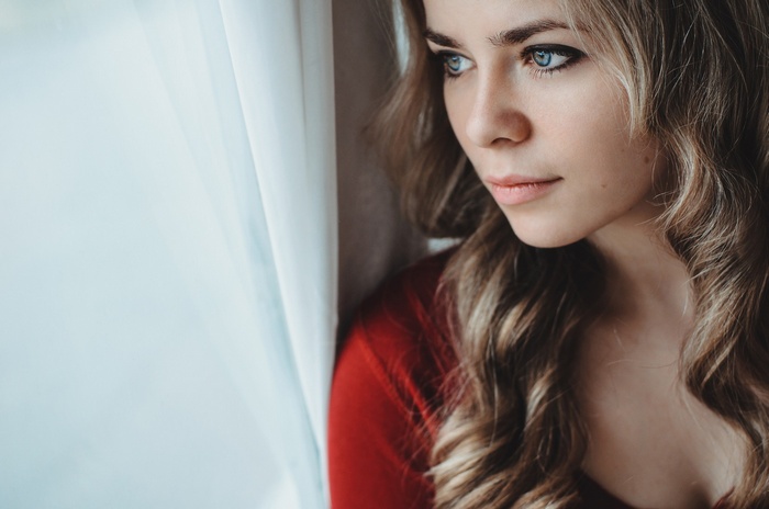 Woman with blue eyes and wavy hair looking out a window