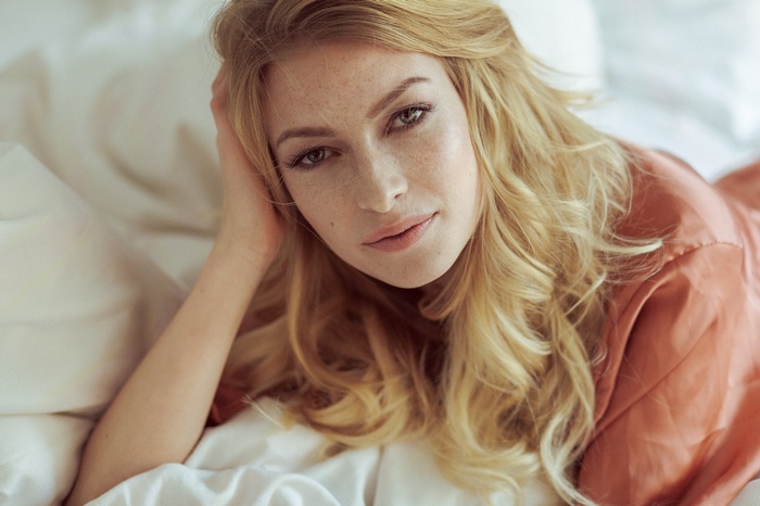 Woman with blonde hair lying on bed