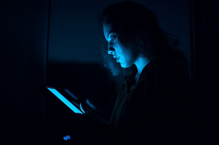 Woman illuminated by a blue light from a device