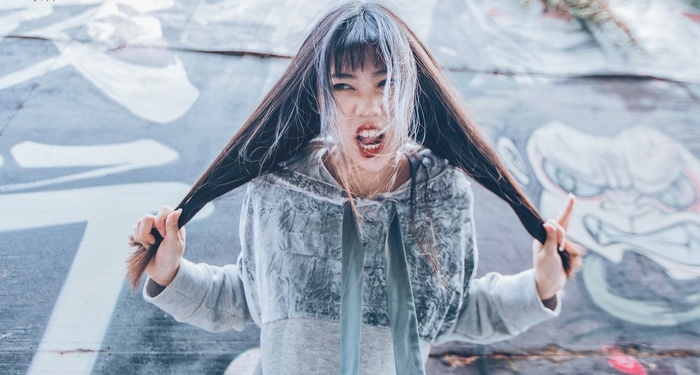 Asian woman with long hair in front of graffiti
