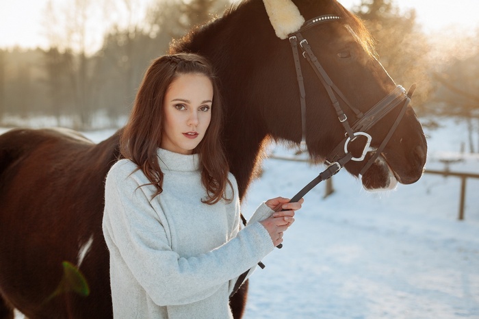 Woman in white sweater with horse in winter