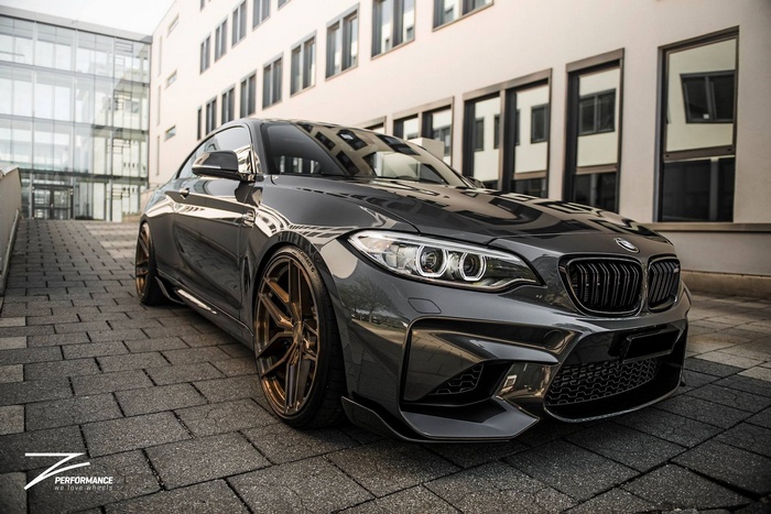 BMW M2 parked on a paved surface in front of a modern building