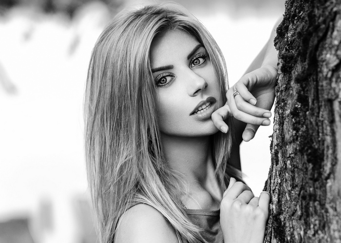 Monochrome portrait of a woman leaning against a tree