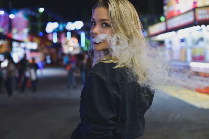 Woman smoking at a carnival at night