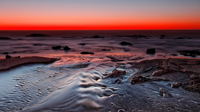 Sunset over rocky beach with ocean waves