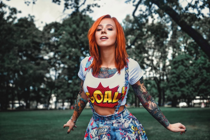 Woman with red hair and tattoos wearing overalls