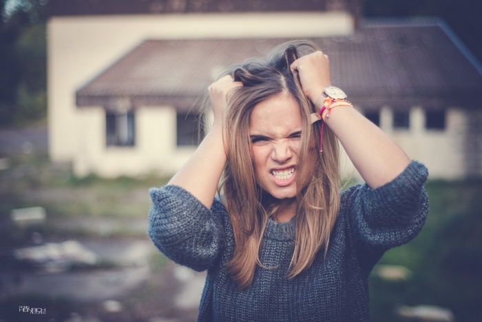 Woman with hands in hair, angry expression