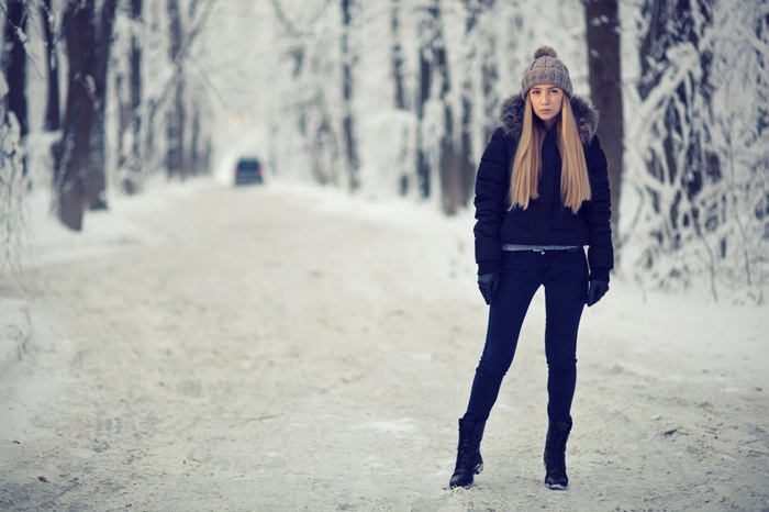 Woman in winter clothes standing on a snowy road