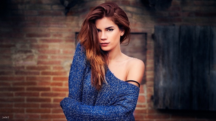 Woman with long wavy hair wearing a blue sweater