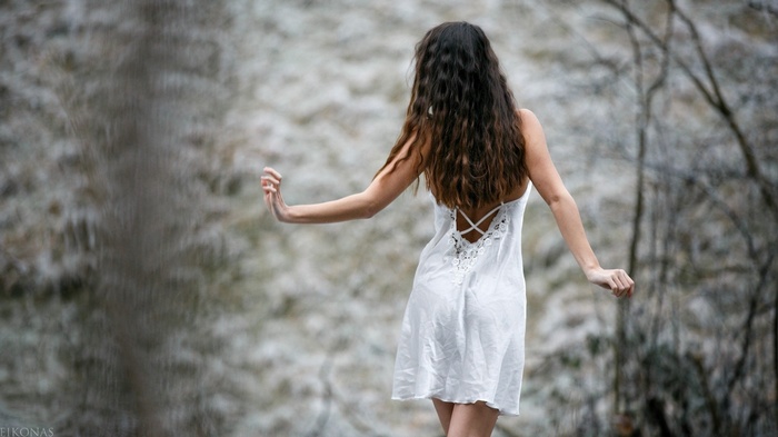 Woman in white dress with long wavy hair from behind