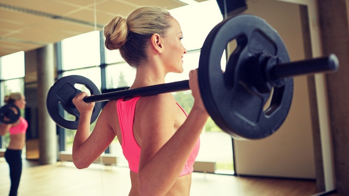 Woman lifting barbell in gym