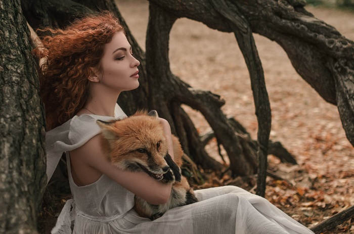 Redhead woman holding a fox in a forest
