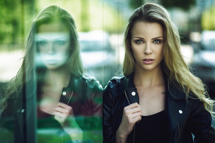 Woman in leather jacket reflected in glass