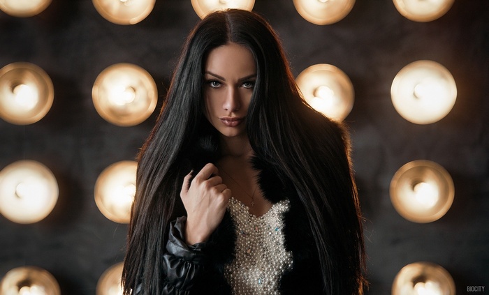 Woman with long dark hair and pearl dress