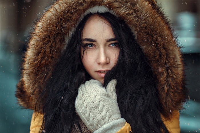 Woman with black hair wearing a fur-lined hood and gloves
