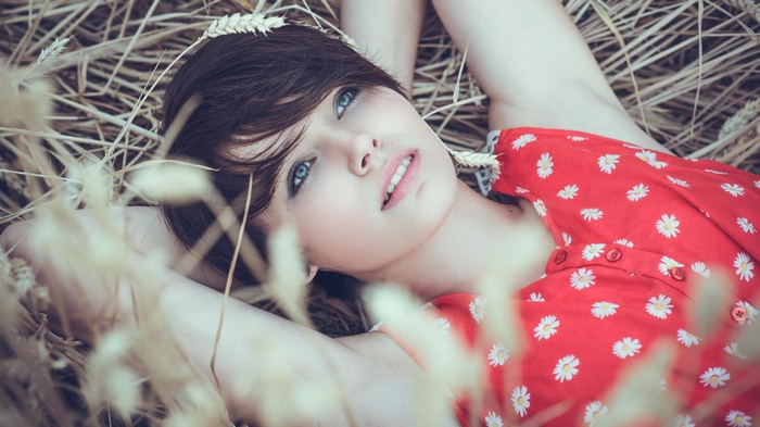 Woman with blue eyes lying in a wheat field
