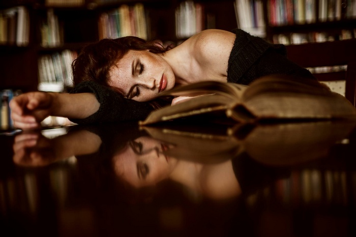 Woman with freckles sleeping on a book