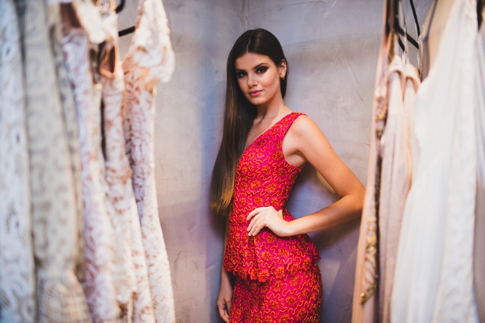 Camila Queiroz in a red dress with dresses on display