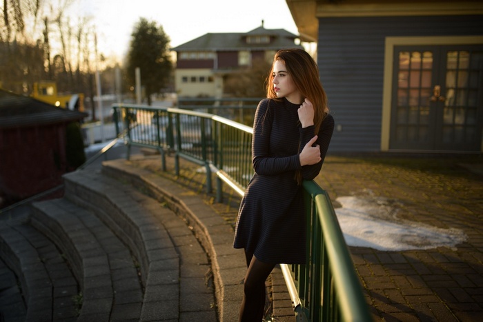 Woman in black dress leaning on railing outdoors