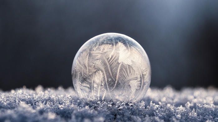 Frozen bubble with frost patterns on snow