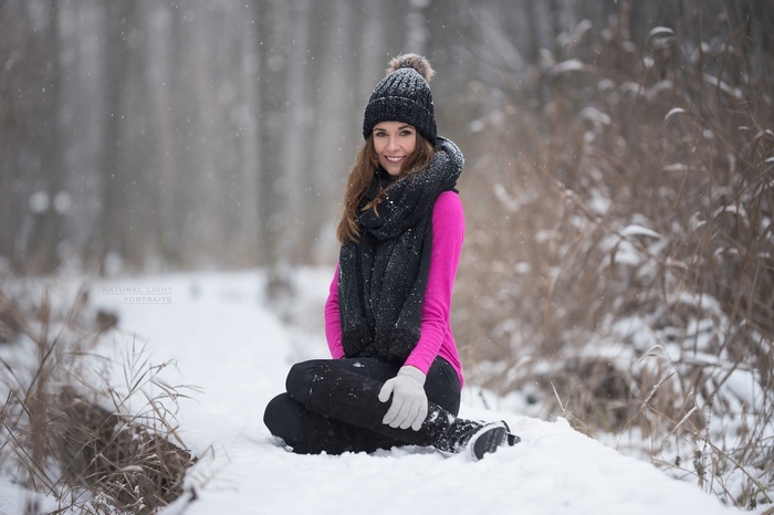 Woman in pink sweater and scarf sitting in snow