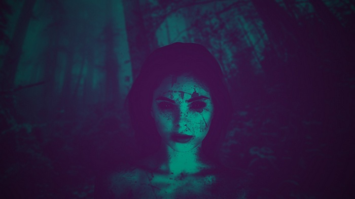Woman with dark eyes and blood splatters in forest