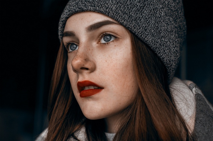 Woman with freckles and red lipstick wearing a beanie