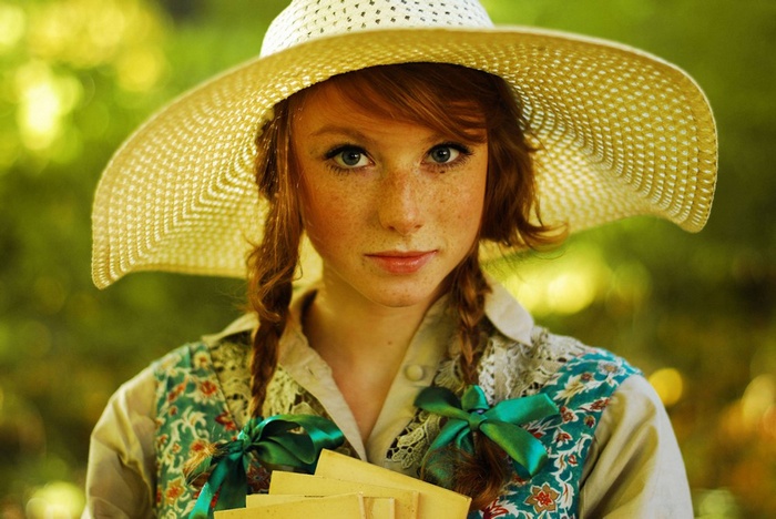 Redhead girl with freckles wearing a straw hat