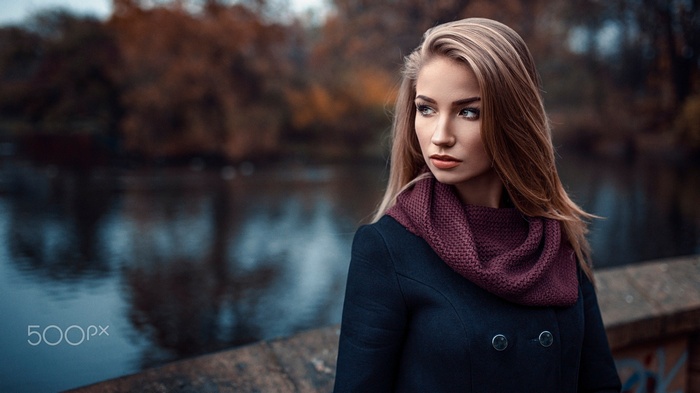 Woman in black coat and scarf looking away by river