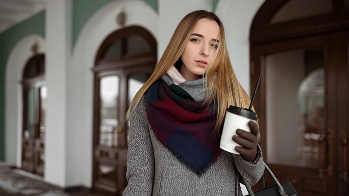 Woman in grey coat holding coffee cup