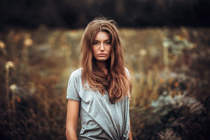 Woman with freckles in a grey t-shirt outdoors
