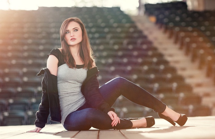 Woman in jeans and heels sitting on stage