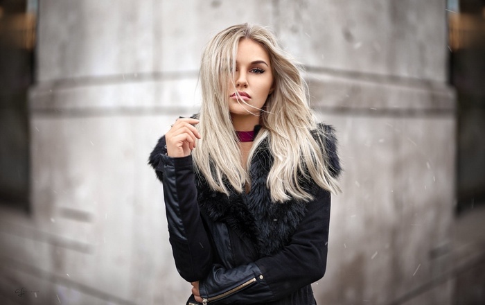 Woman with blonde hair wearing a black jacket outdoors