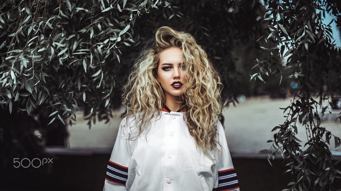 Woman with blonde curly hair and dark lipstick