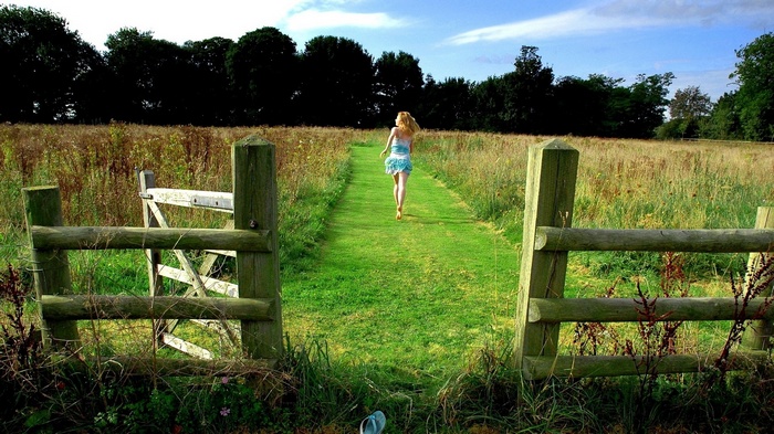 Woman running on a grassy path through a field